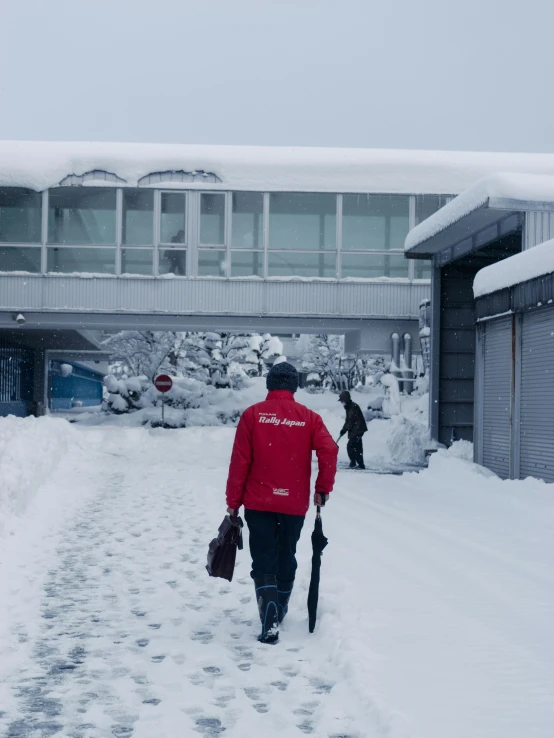 two people walk through the snow in front of a building