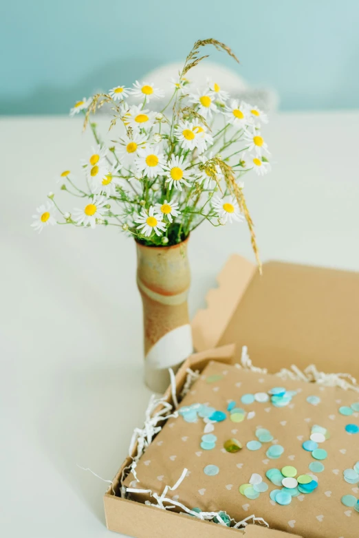 flowers in a vase sitting on a box, on a table