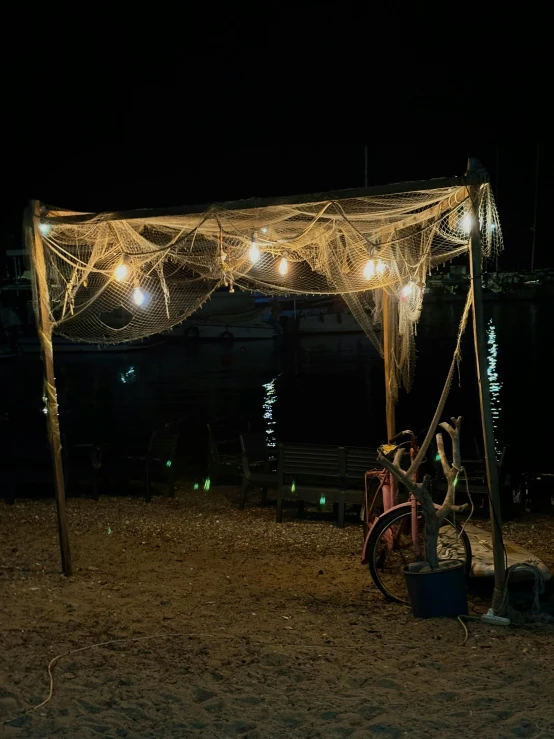 a beach area covered in nets with lights