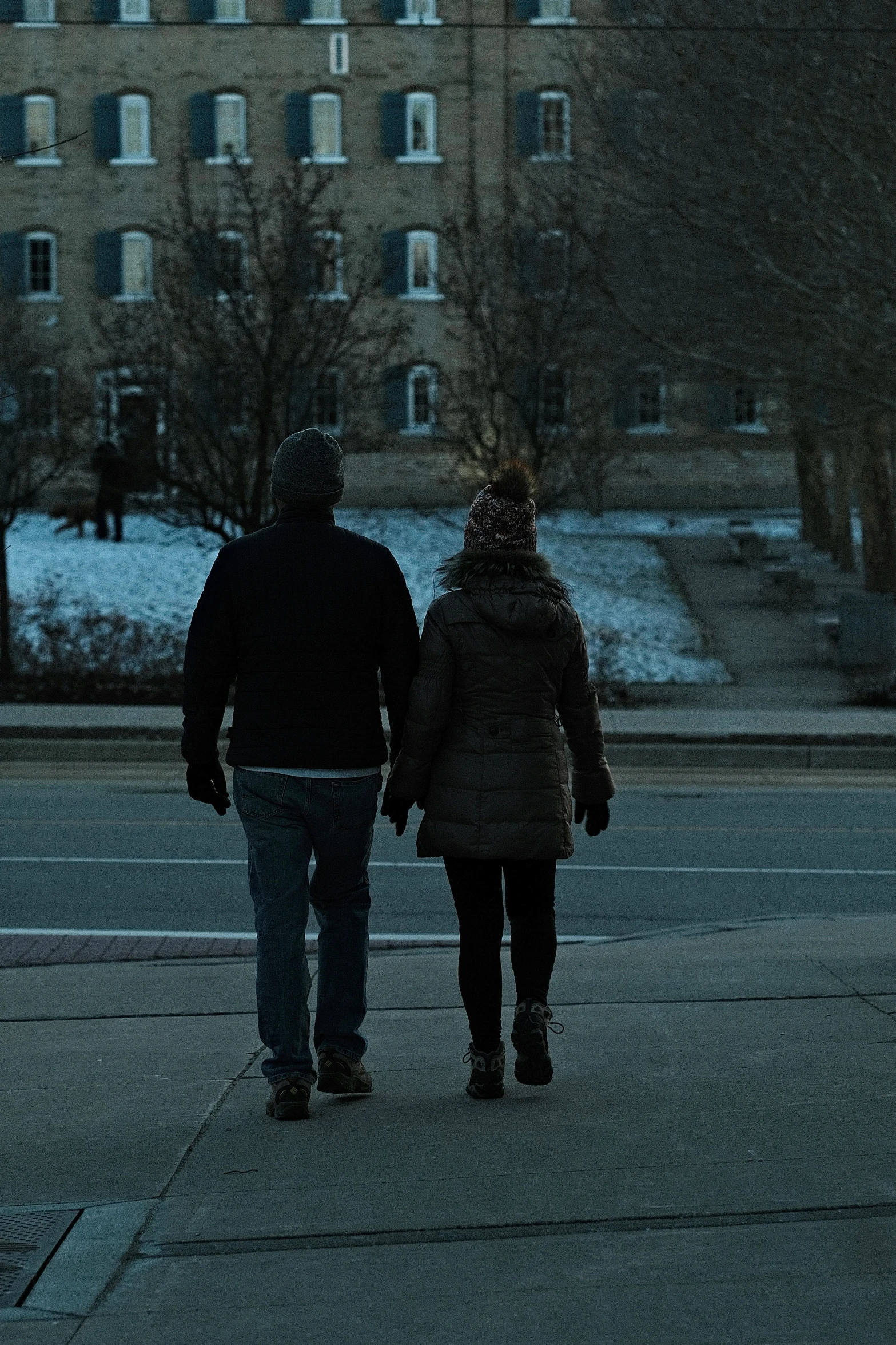 a man and woman walking on a street in the dark