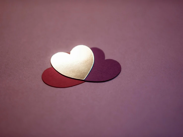 two hearts cut out of paper on a purple surface