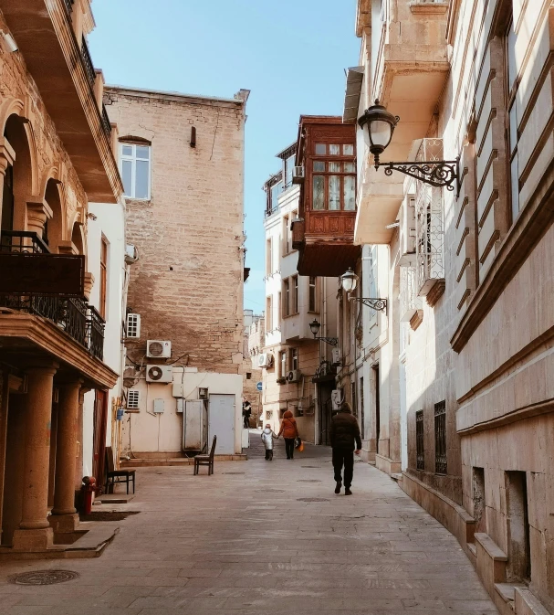 two people walking down an alley with stone buildings