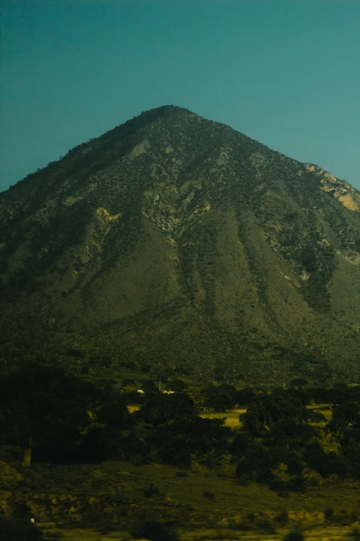 the view of a mountain near many fields and trees