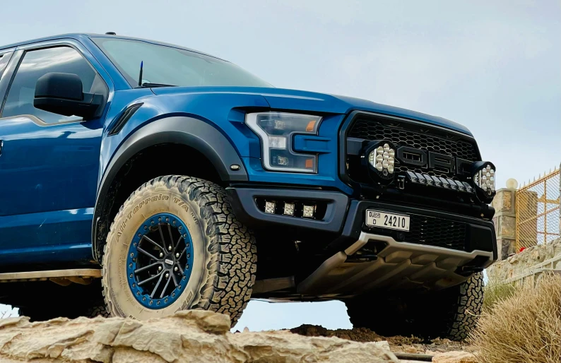 a large blue truck driving through some rocks