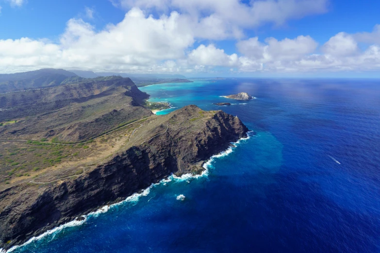 a blue ocean that is surrounded by mountains and a few clouds