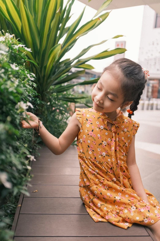 a girl wearing a flowery dress sits on the ground