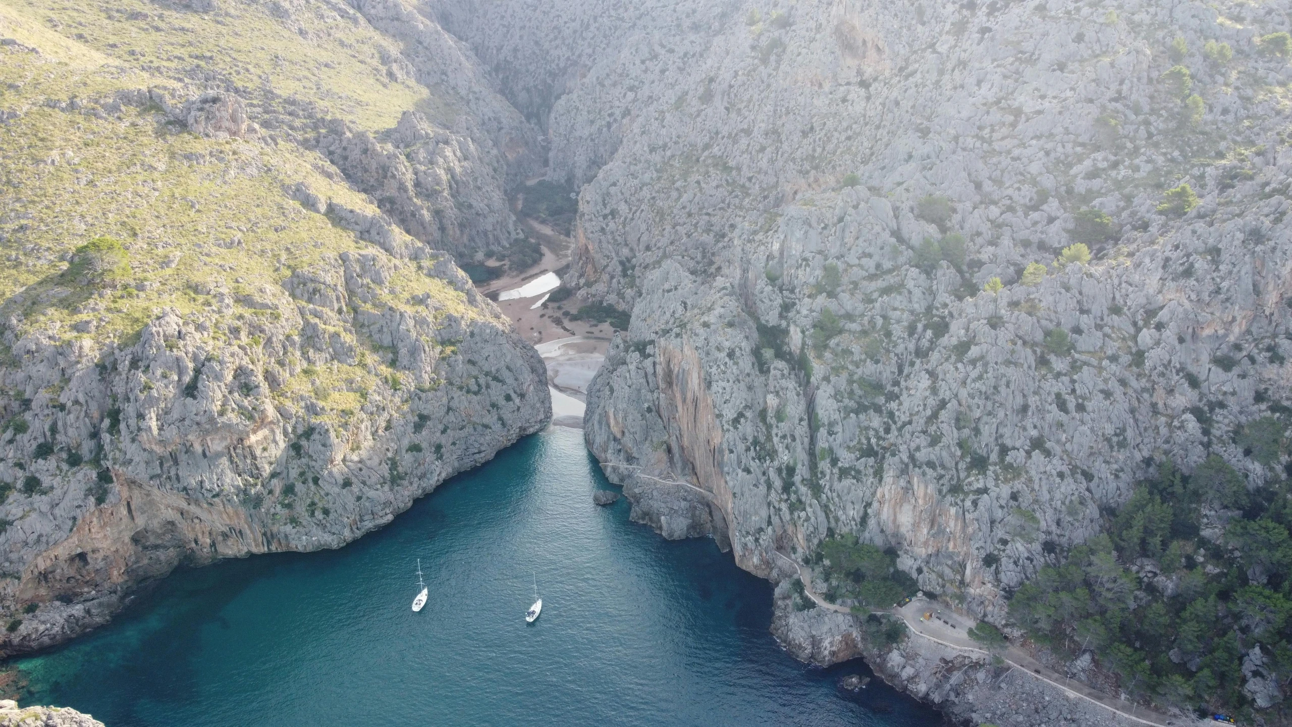 three boats are near a river in an area with very steep cliffs