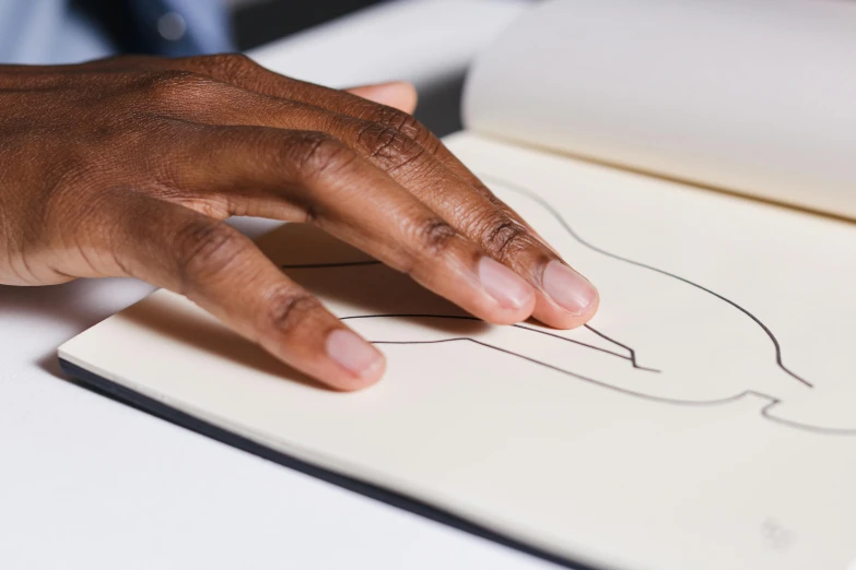 a persons hand pointing on a drawing of a hand holding a piece of paper