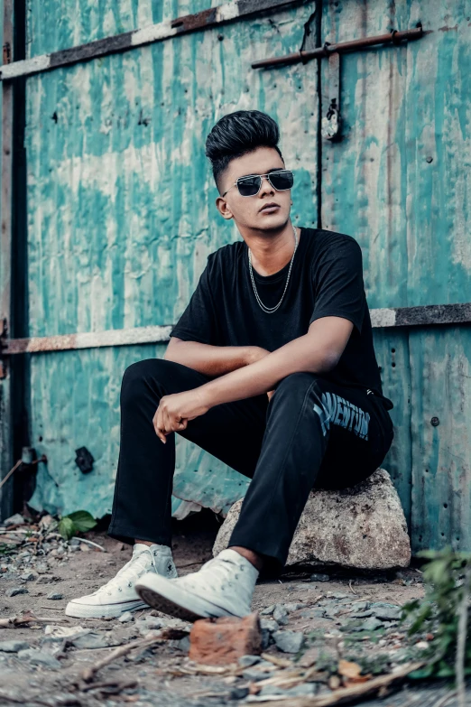 a man is posing on the concrete and wearing sunglasses