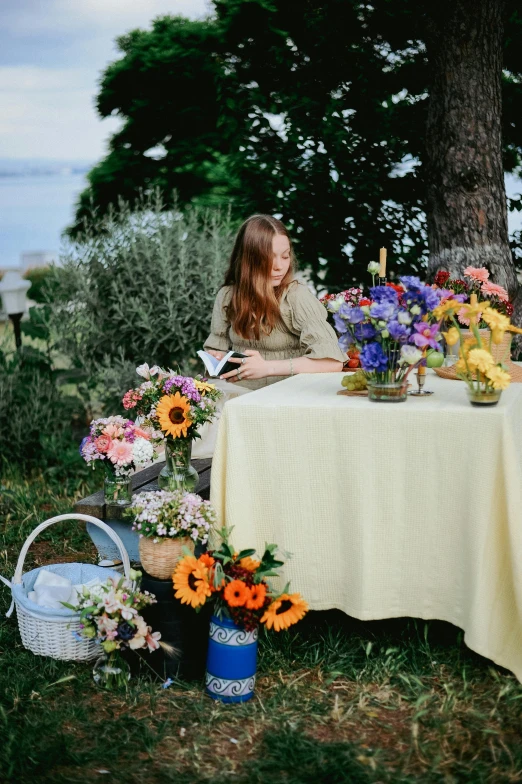 a woman is sitting at a table surrounded by flowers