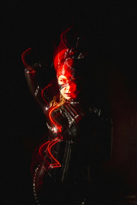 the woman in latex is lit up in red and black