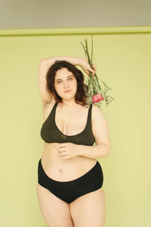 a woman in a black bikini holding a flower