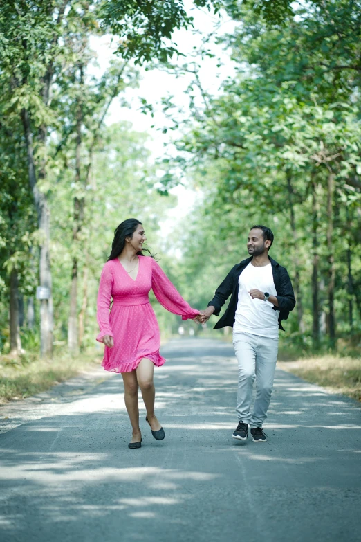 a man and woman holding hands, walking down the road together