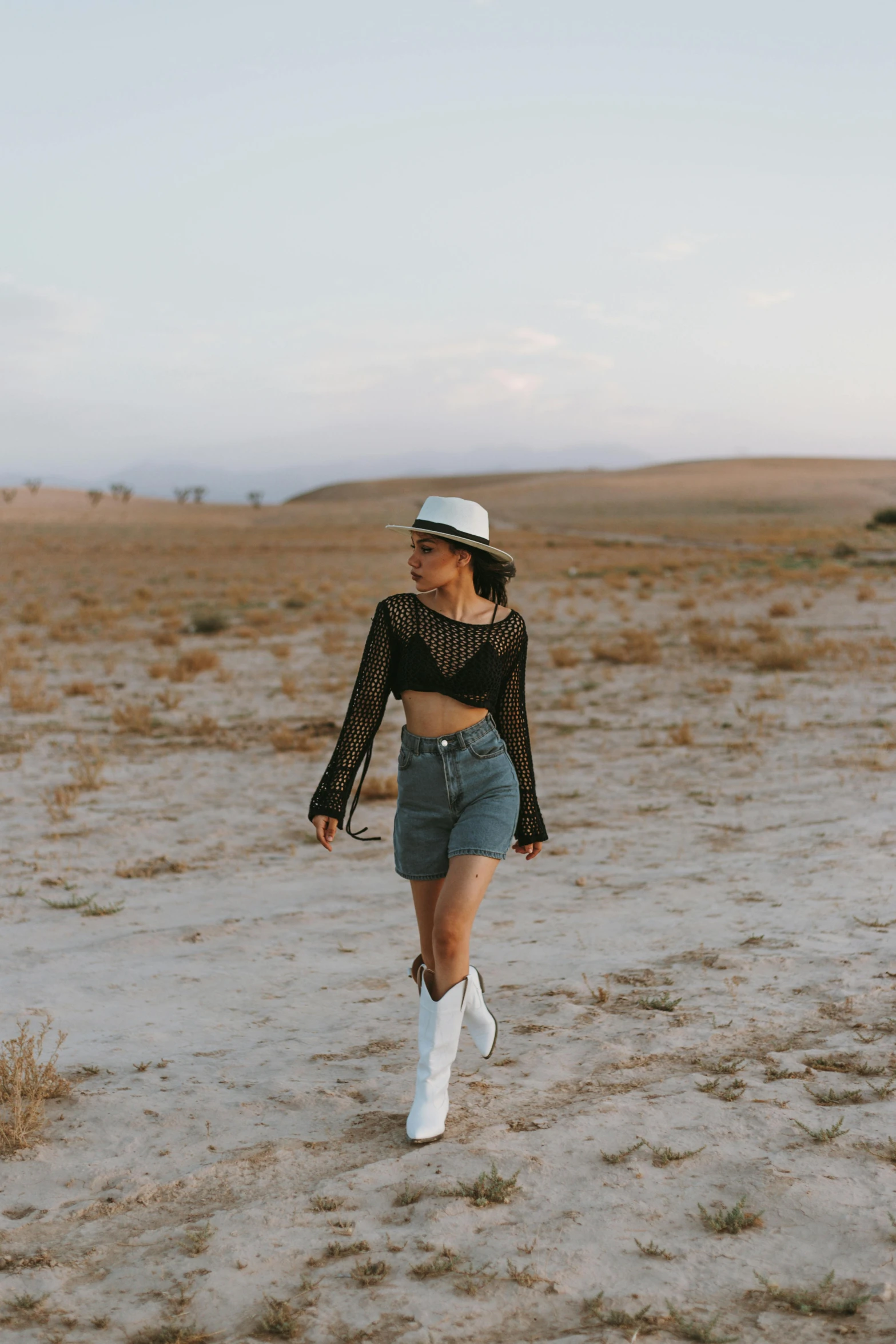 a woman in short blue shorts is standing in the middle of a desert