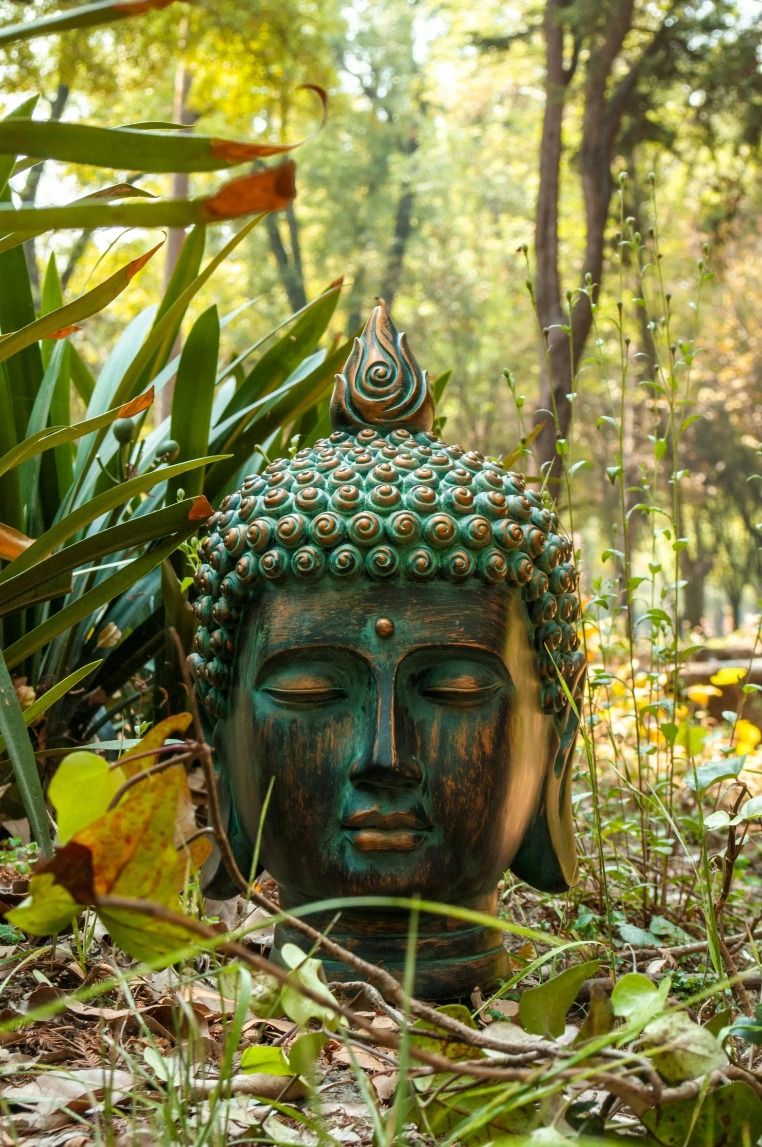 a small statue is in the grass by some plants