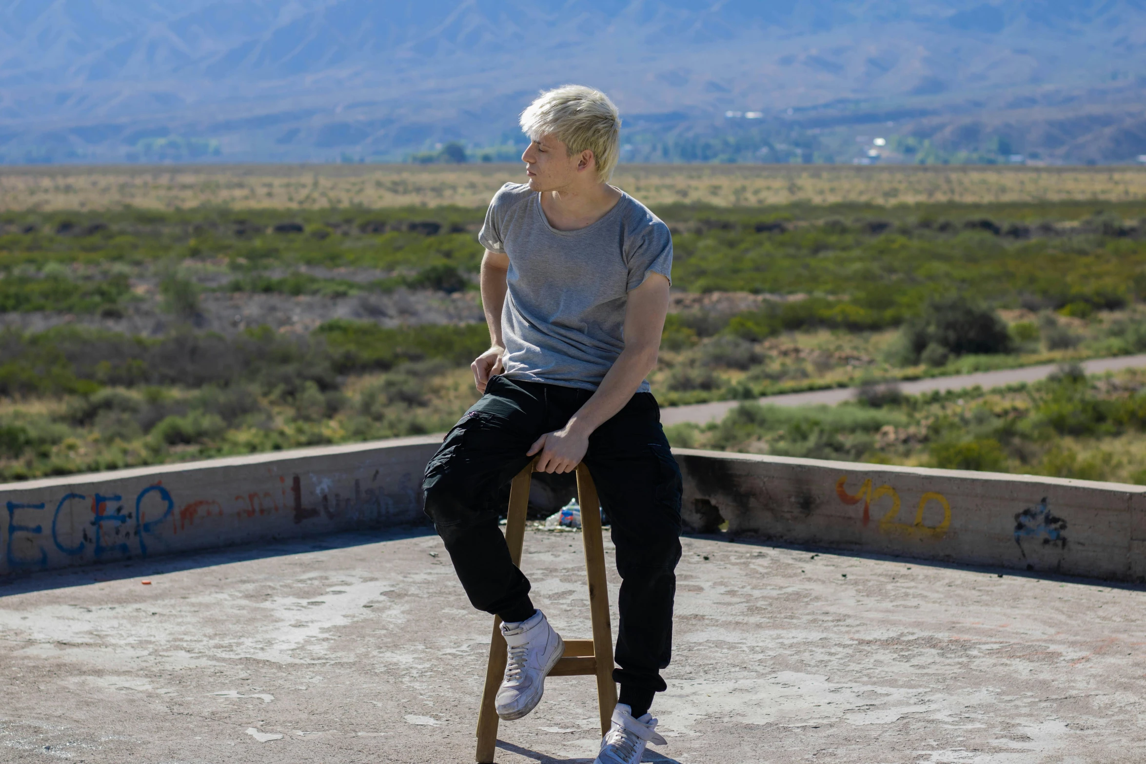 a man is sitting on a chair in the middle of a field