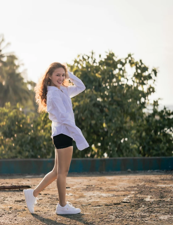 a woman with curly hair, in shorts, a shirt and sneakers, and some tennis rackets