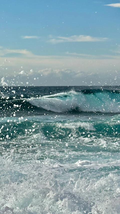 an ocean waves on the beach with the blue sky