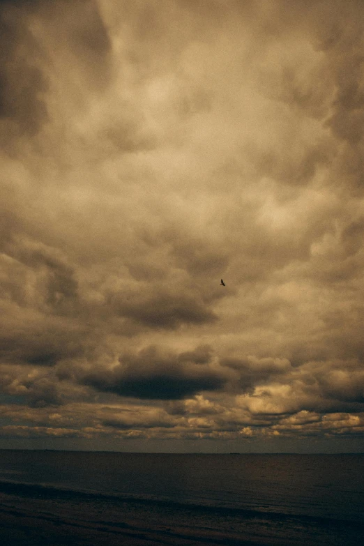 a jet flies over the ocean under dark clouds