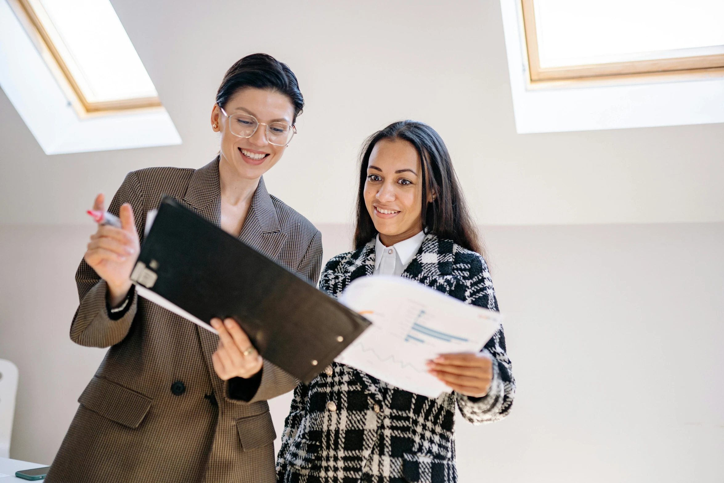 two woman standing next to each other in a room