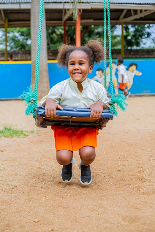 an image of a little girl playing on a swing