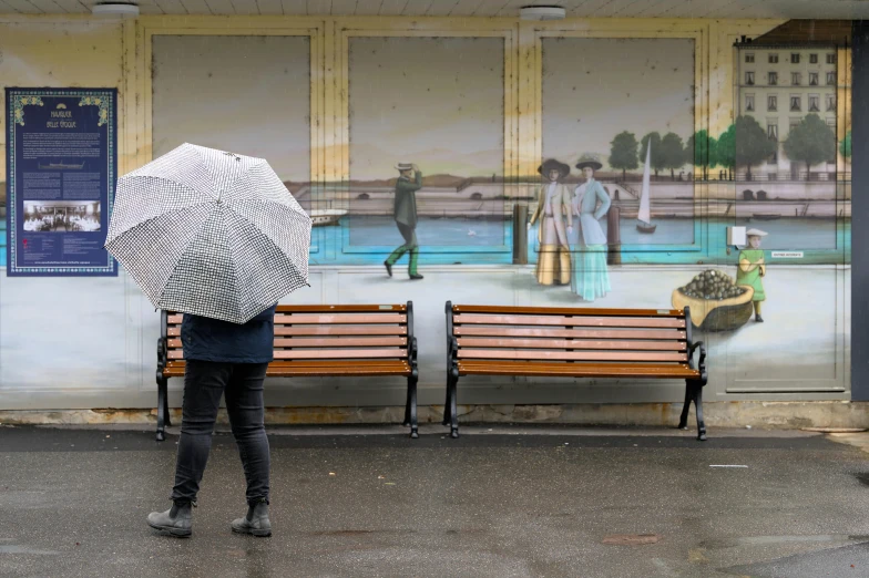 a person with an umbrella walking by some benches