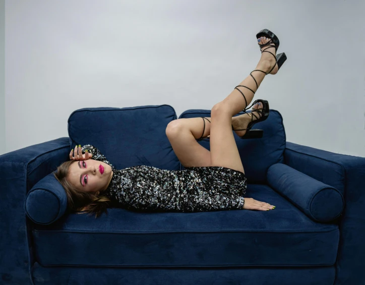 woman wearing black dress laying on blue couch