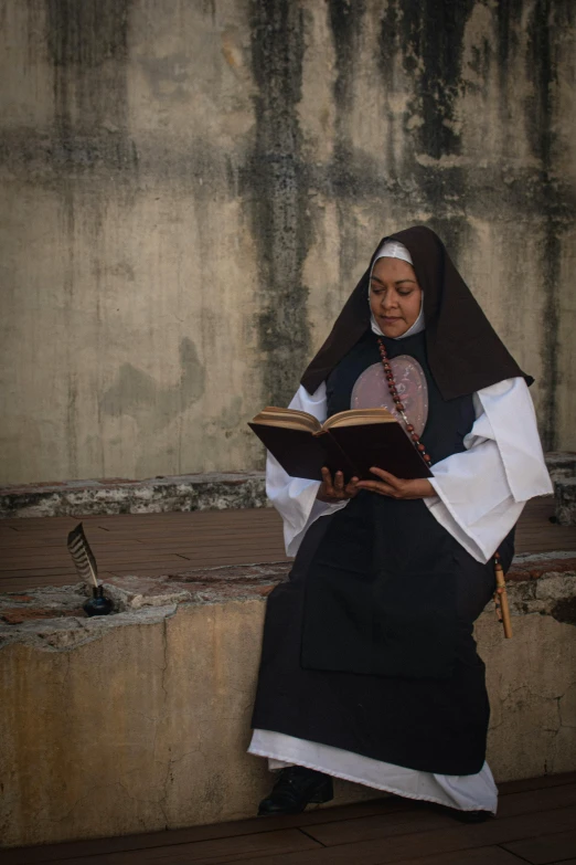 a woman sitting on a ledge with a book