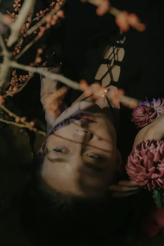 a woman laying in the grass near flowers