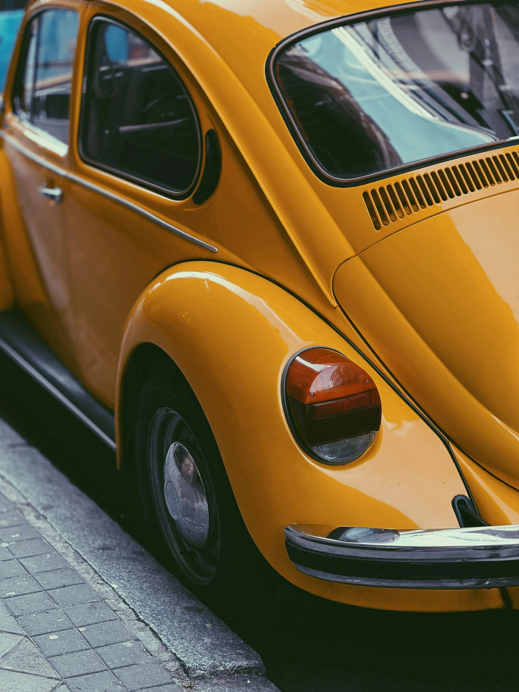 yellow volkswagen bug parked in a row on the side of the road