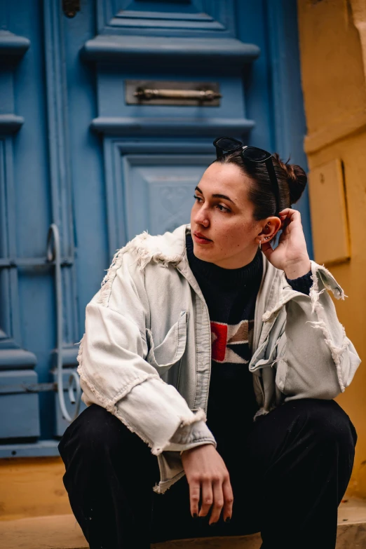 a woman holding a cell phone up to her ear while sitting