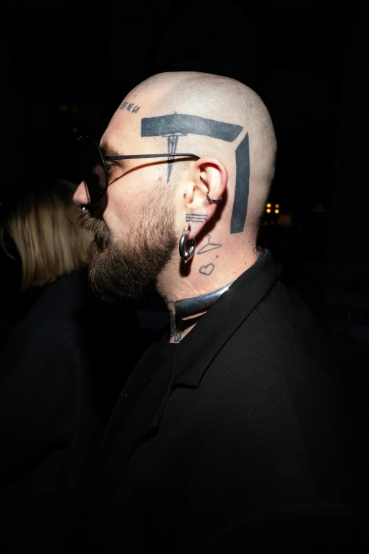 a bald man wearing sunglasses and a t tattoo