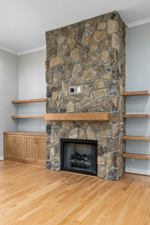 a room has a stone fireplace and shelfs