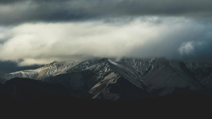 mountains with white snow on them under a cloudy sky