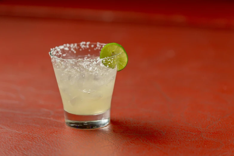 a drink sits on a table with limes in it