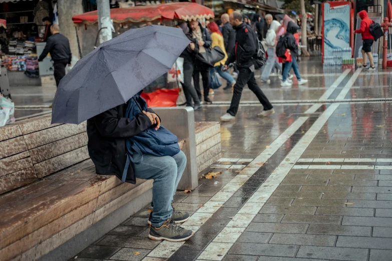 woman holding an umbrella sitting on a bench