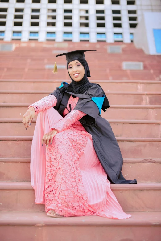 a woman in a graduation gown sitting on some steps