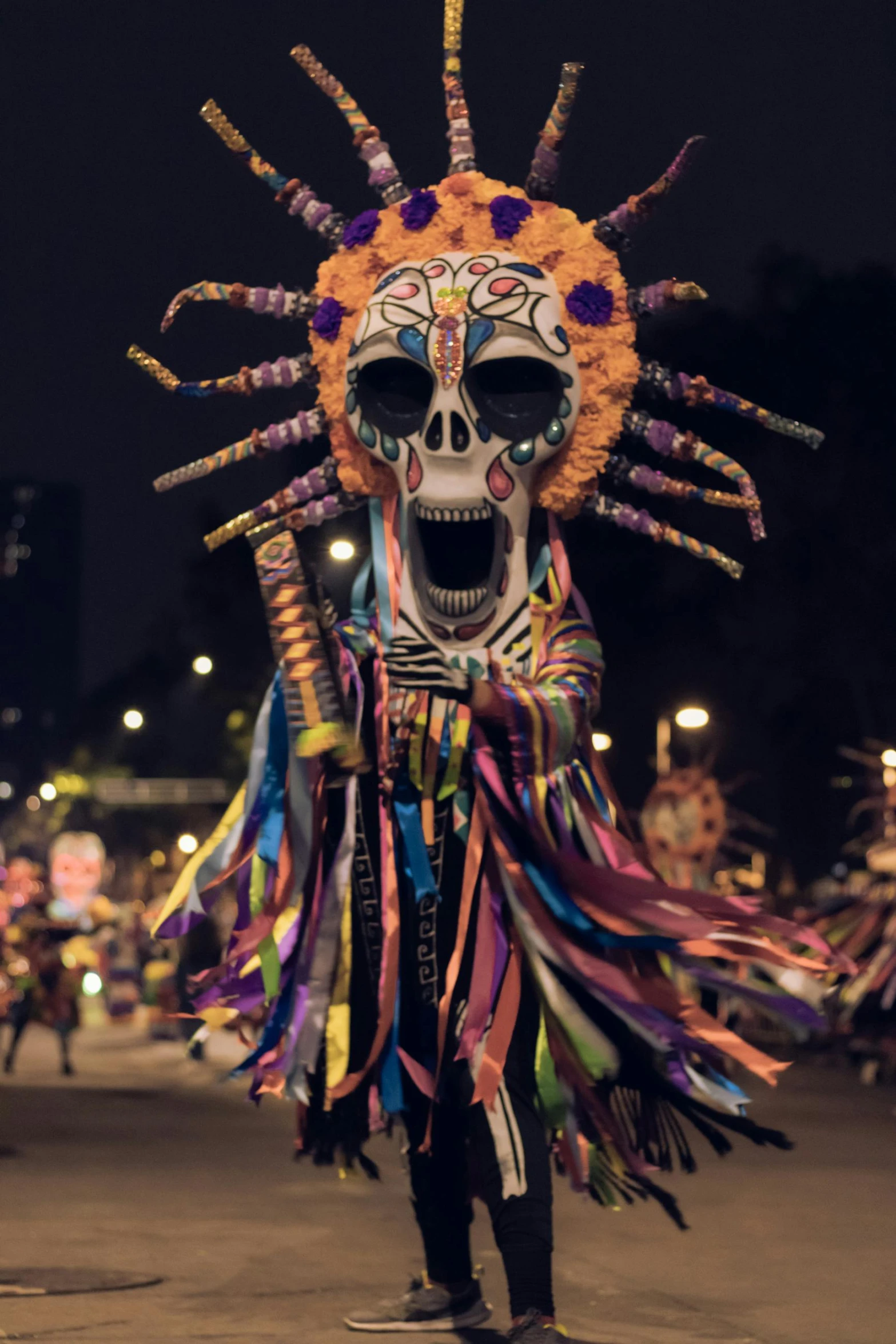 a woman in a colorful mask and costume walking in the street