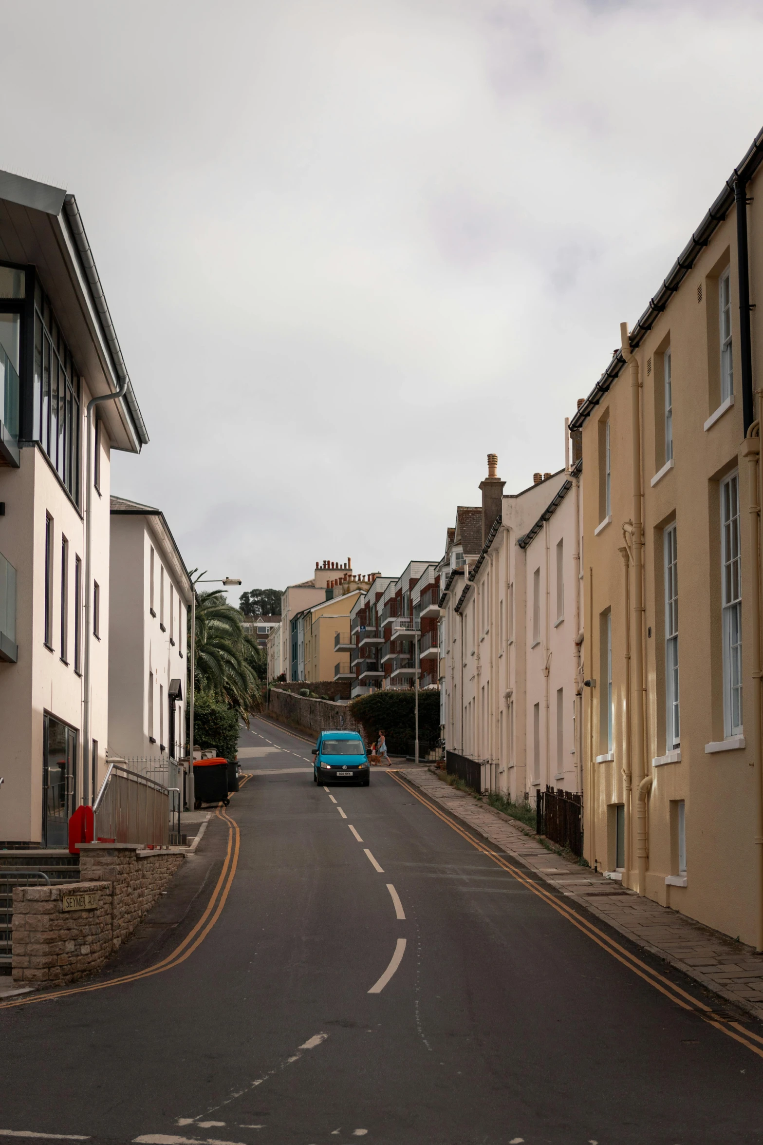 a blue bus traveling down a street next to tall buildings