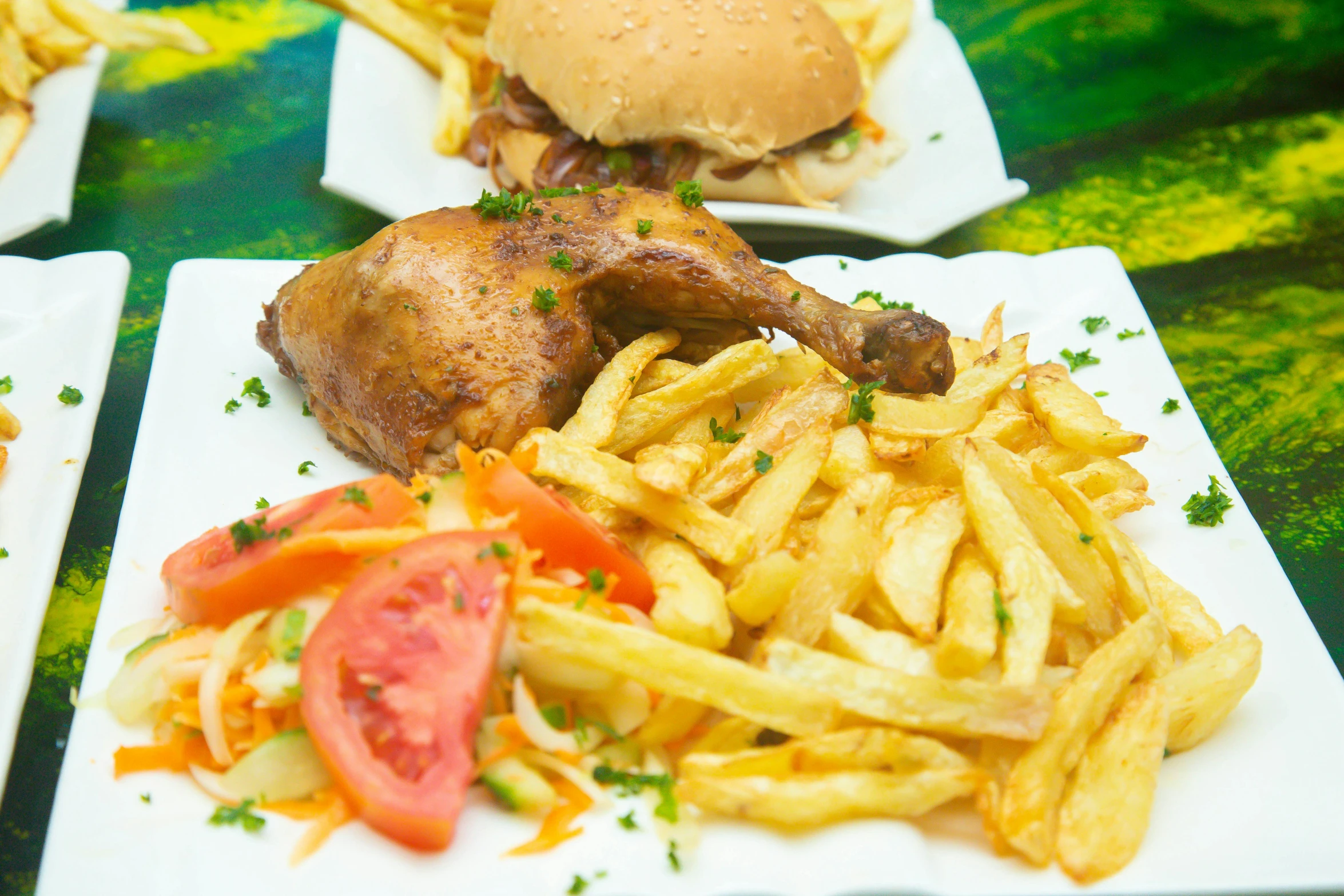 some fries, tomatoes, and a chicken sitting on plates