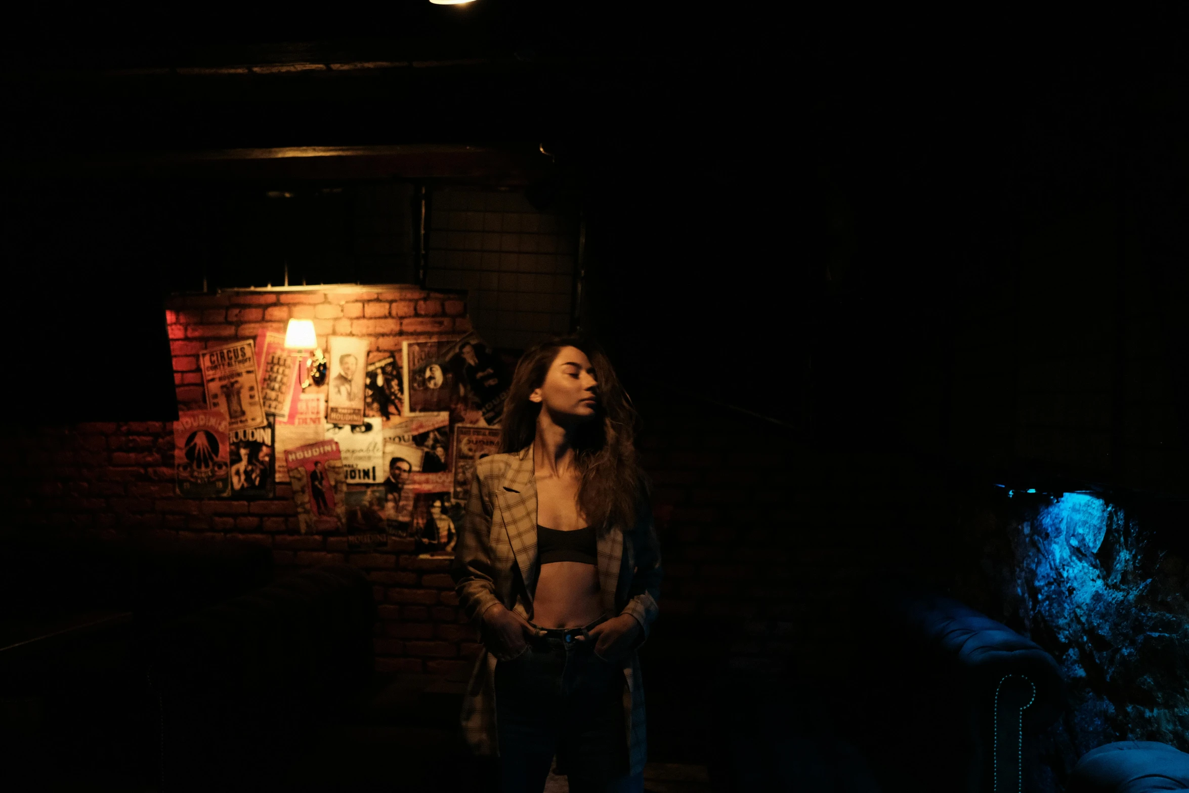 a woman standing in front of a brick wall at night