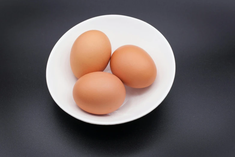 three eggs in a bowl on a table