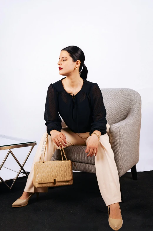 a woman is posing on a chair with a handbag