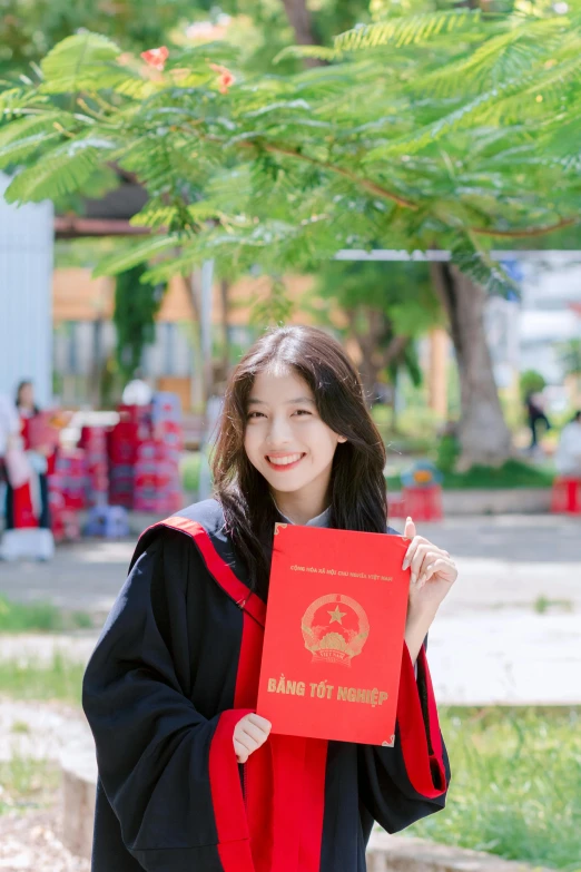 a female student wearing a red and black gown holding a red paper