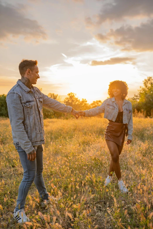 a man and woman standing in a field touching hands