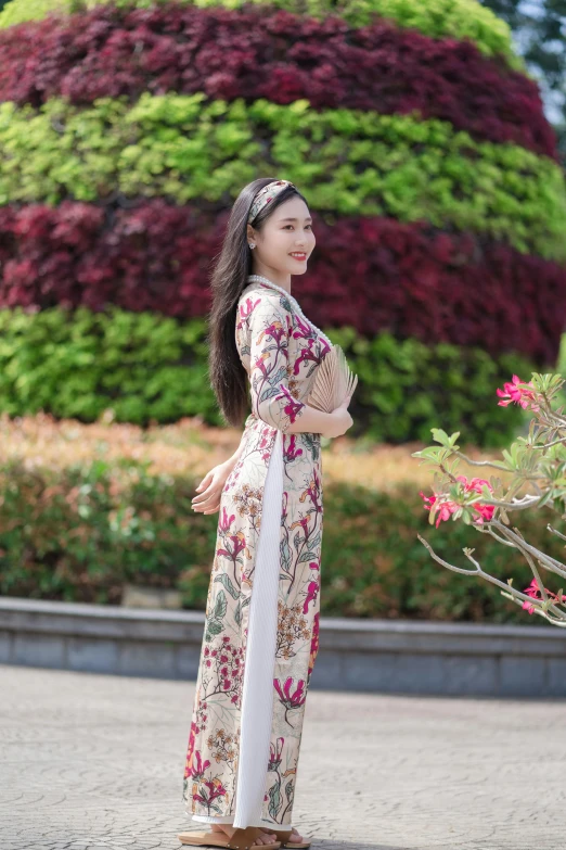 a woman stands in front of a very colorful flowery arrangement