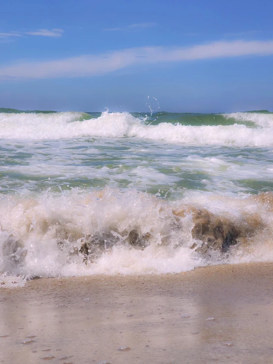 a beach scene with blue skies and waves rolling in to shore