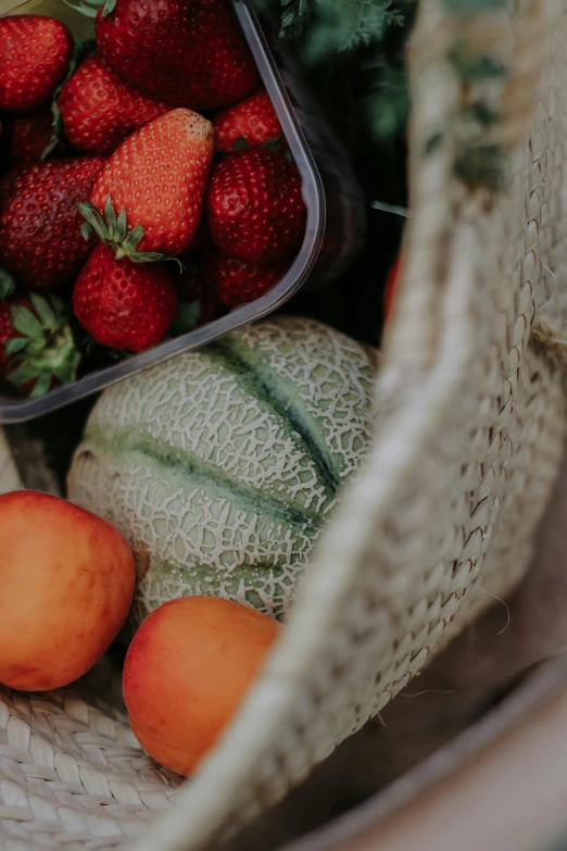 a basket with strawberries and watermelon and two melons