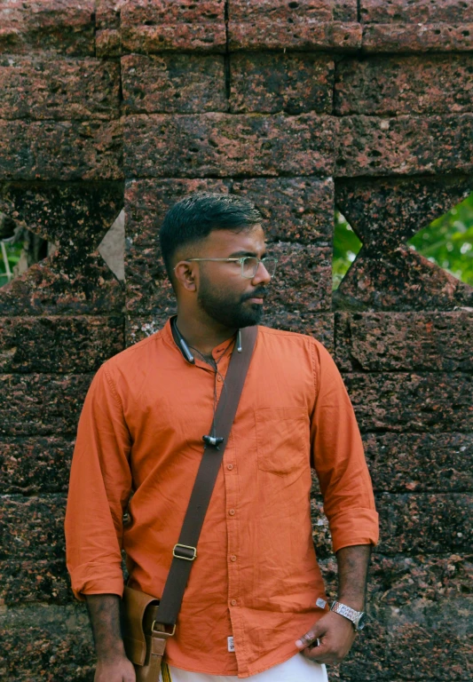 a man in an orange shirt with a small brown purse