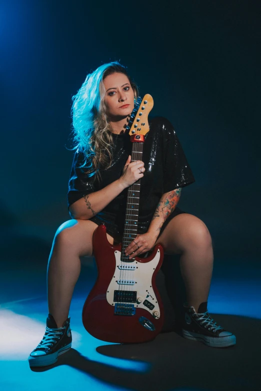 lady sitting down playing the guitar with the light from behind her